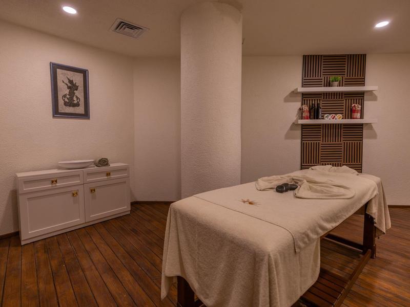 Calm, comfortable massage room with beige table and warm wooden floor.