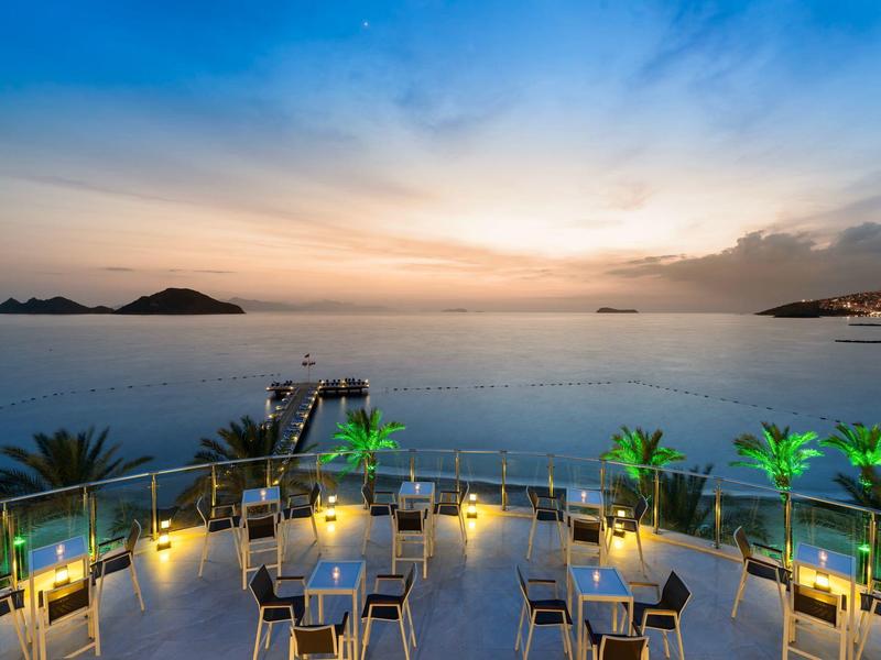 Terrace with tables and chairs overlooking the sea at sunset