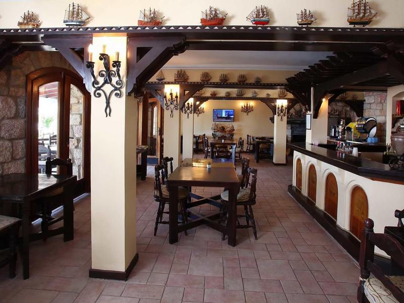 Rustic hotel restaurant with wooden ceiling, stone pillars, and cozy atmosphere.