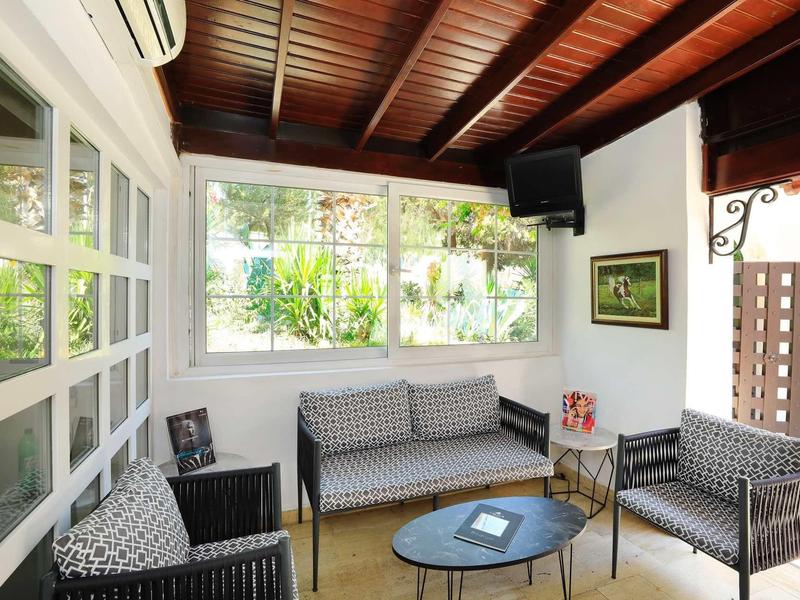 Cozy waiting area with armchairs, sofa, glass table, and large windows in a hotel.