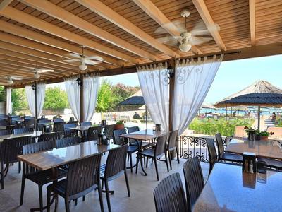 Terraza de restaurante al aire libre con mesas, sillas negras y techo de madera en hotel.
