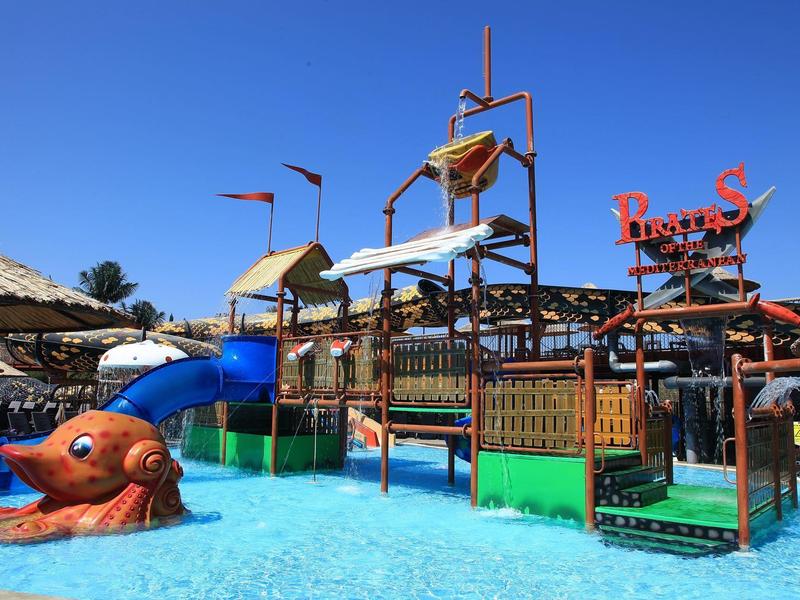 Un colorido parque acuático con toboganes y piscina en el área exterior de un hotel.