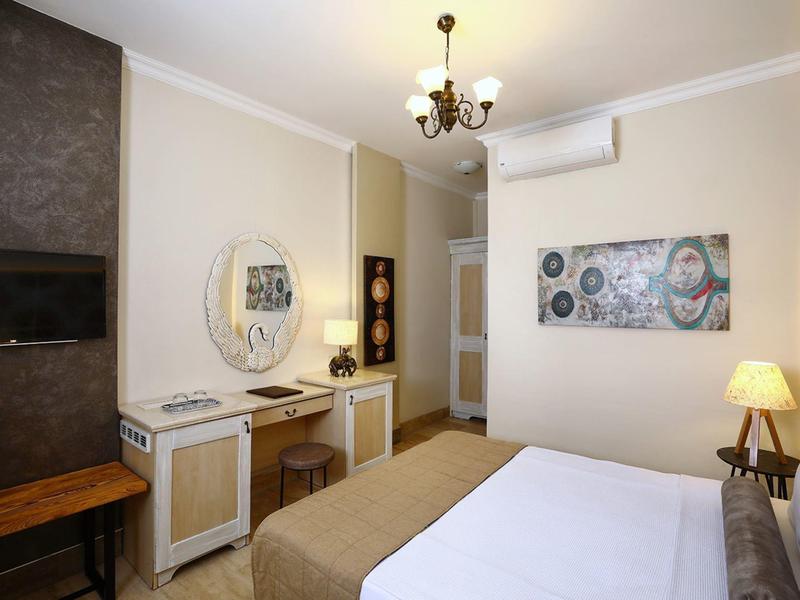 Habitación de hotel con cama doble, tocador con espejo, televisión en la pared y lámpara de pie.