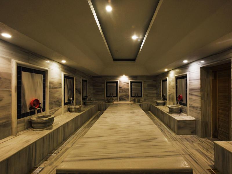 Área de spa elegante con revestimiento de madera, gran superficie para acostarse e iluminación relajante.
