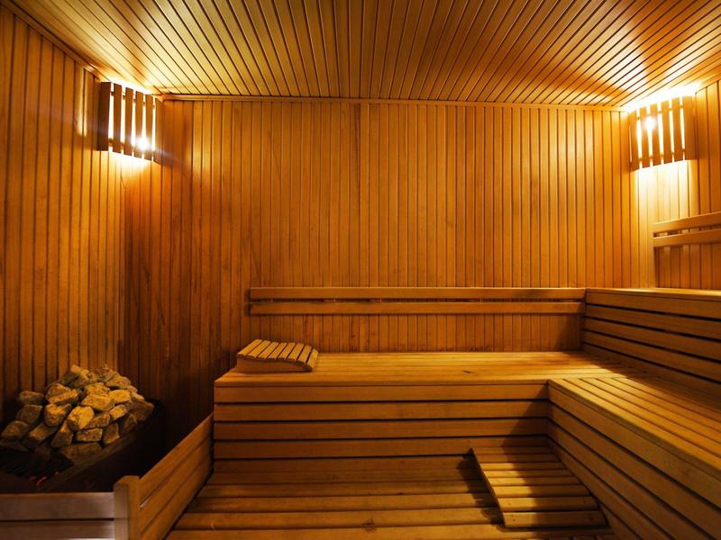 Sauna finlandesa cálida con revestimiento de madera, bancos y piedras para la estufa sauna.