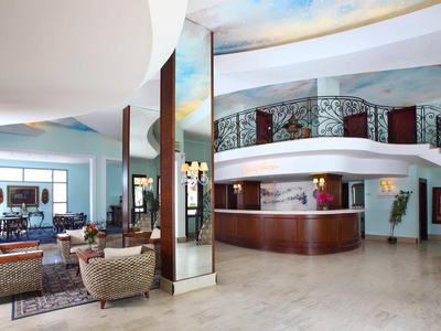 Grand hall d'hôtel avec réception, sièges et escalier en colimaçon.