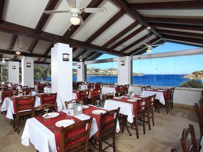 Restaurant avec mobilier en bois et vue sur la mer sous un toit ouvert.