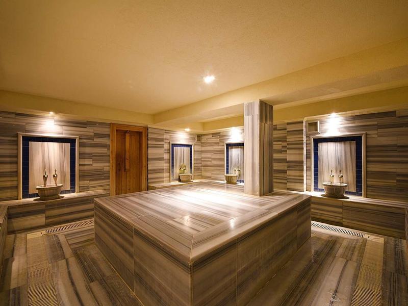 Salle de vapeur moderne avec sièges et éclairage doux dans des tons marron atténués.
