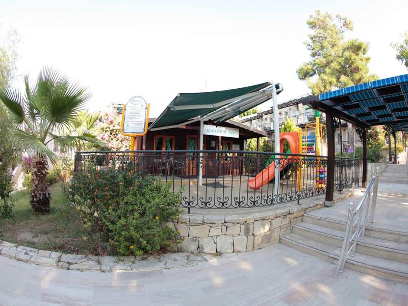 Espace extérieur d'hôtel avec aire de jeux, toboggan et coin repas couvert