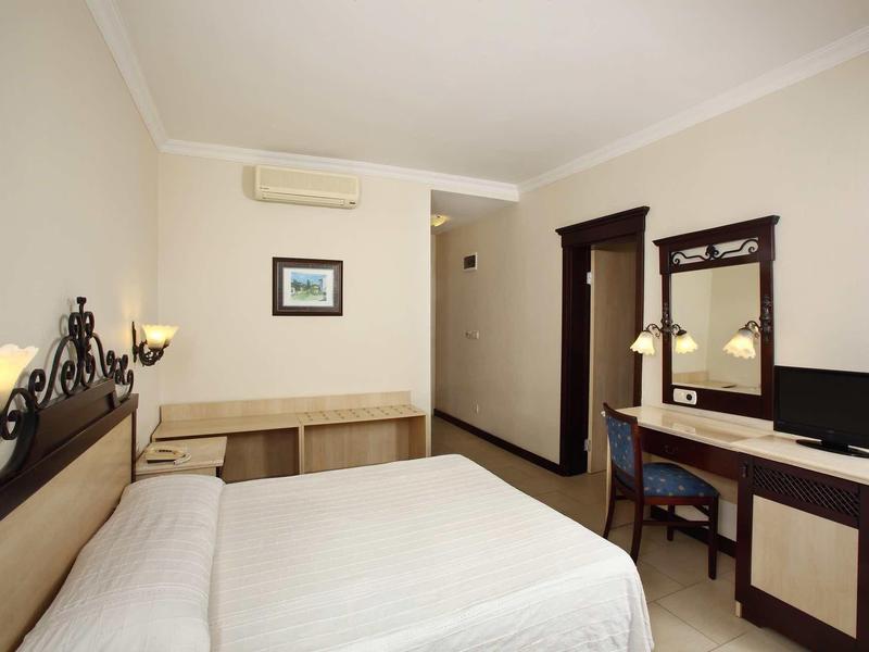 Chambre d'hôtel simple avec lit double, bureau, chaise et climatisation.