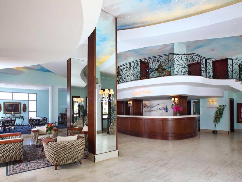Grand hall d'hôtel avec réception, sièges et escalier en colimaçon.