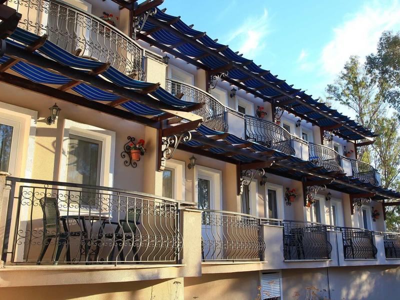 Hôtel à plusieurs étages avec balcons et chaises sous un ciel bleu.