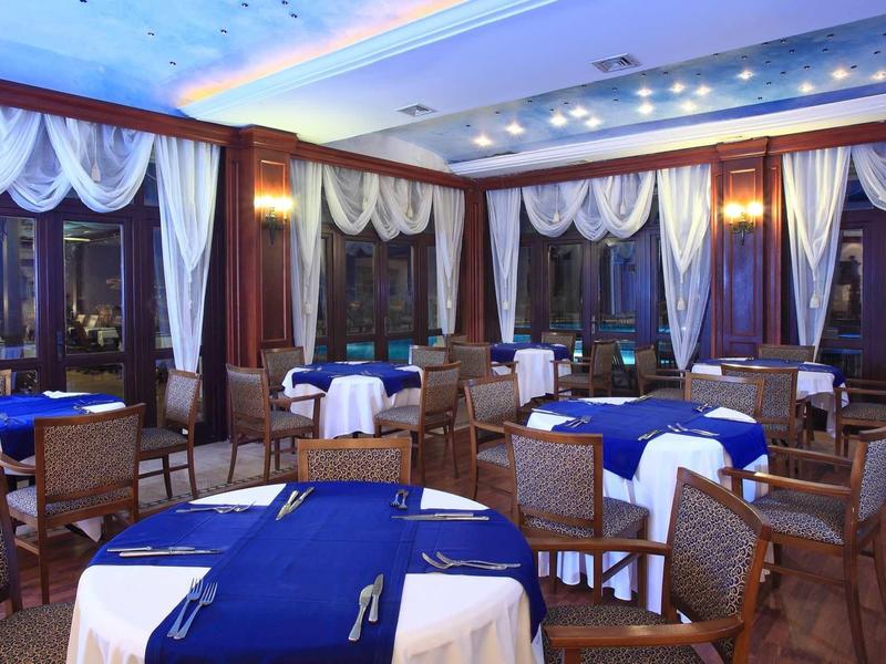 Ein elegantes Restaurant mit runden Tischen, blauen Tischdecken und braunen Holzstühlen.