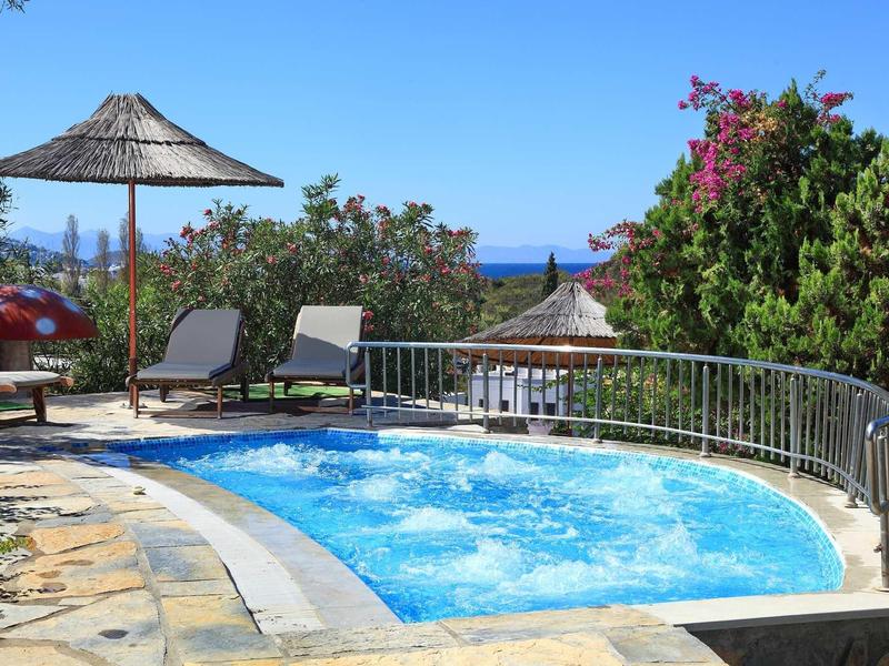 Kleiner Pool mit Sprudelwasser, Liegestühlen und Sonnenschirmen in mediterraner Gartenanlage.