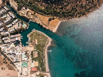 Vue aérienne d'une côte avec plage, marina et structures hôtelières.