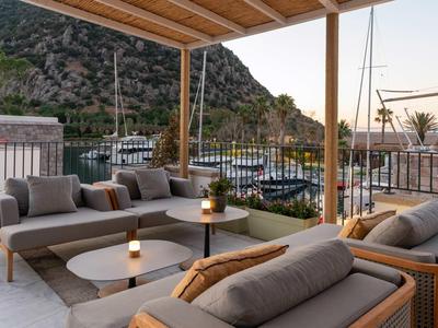Moderner Außenbereich mit gemütlichen Sitzmöbeln und Blick auf das Meer und Berge bei Dämmerung.