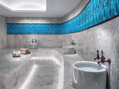 Bain en marbre moderne avec mur bleu et robinetterie en bronze.