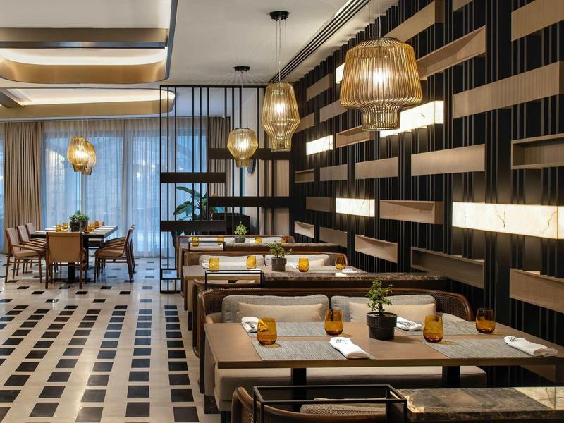 Salle de restaurant moderne avec tables, chaises et éclairages suspendus élégants.