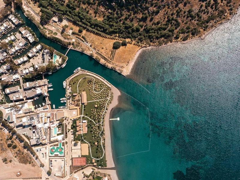Vue aérienne d'une côte avec plage, marina et structures hôtelières.