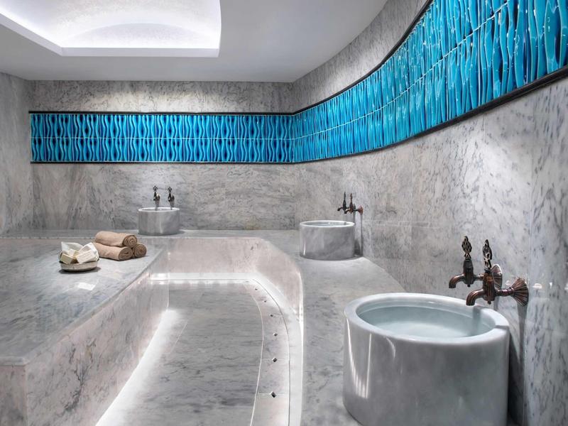 Bain en marbre moderne avec mur bleu et robinetterie en bronze.