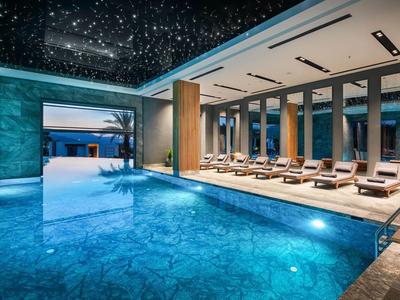 Modern indoor pool with starry ceiling and sun loungers in a relaxing hotel atmosphere