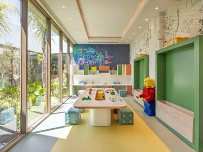 Bright children's playroom with tables, cube seats, and large window overlooking garden