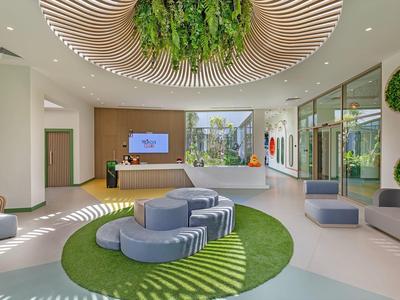 Bright hotel lobby with green plants, circular seating, and modern design.