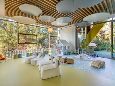 Bright kindergarten room with large windows, seating, toys, and outdoor access.
