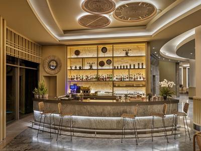 Modern hotel bar area with illuminated counter and elegant bar stools in warm tones.