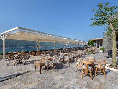 Large terrace with many tables and chairs under a blue sky overlooking the sea.