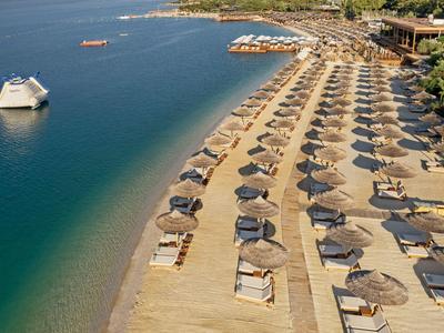 Strand met rijen ligbedden en parasols bij helder zee naast hotelresort