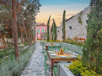 Cozy hotel outdoor terrace with set tables and plants along a stone-paved path.