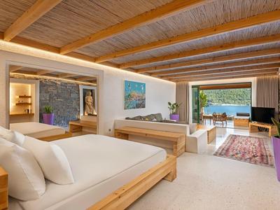 Modern hotel room with two beds, wooden ceiling, and view of terrace and sea.