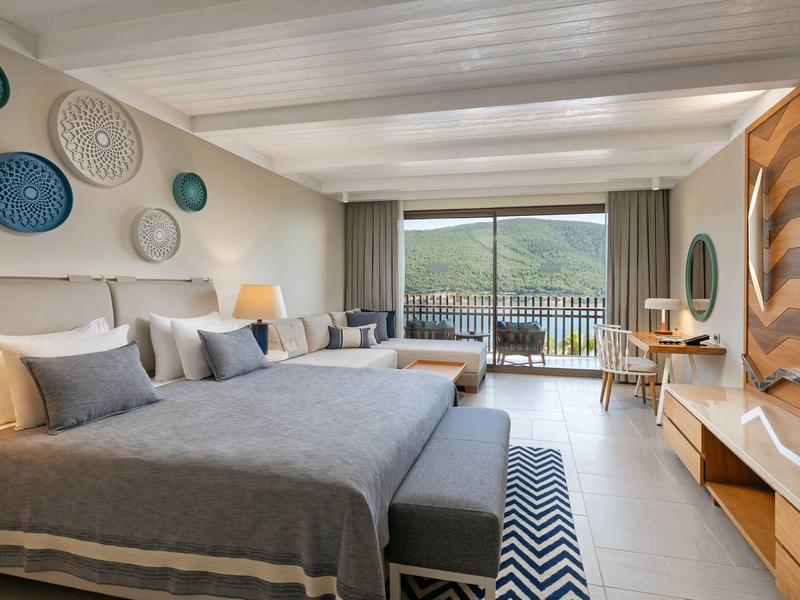 Modern hotel room with two large beds and mountain view from balcony.