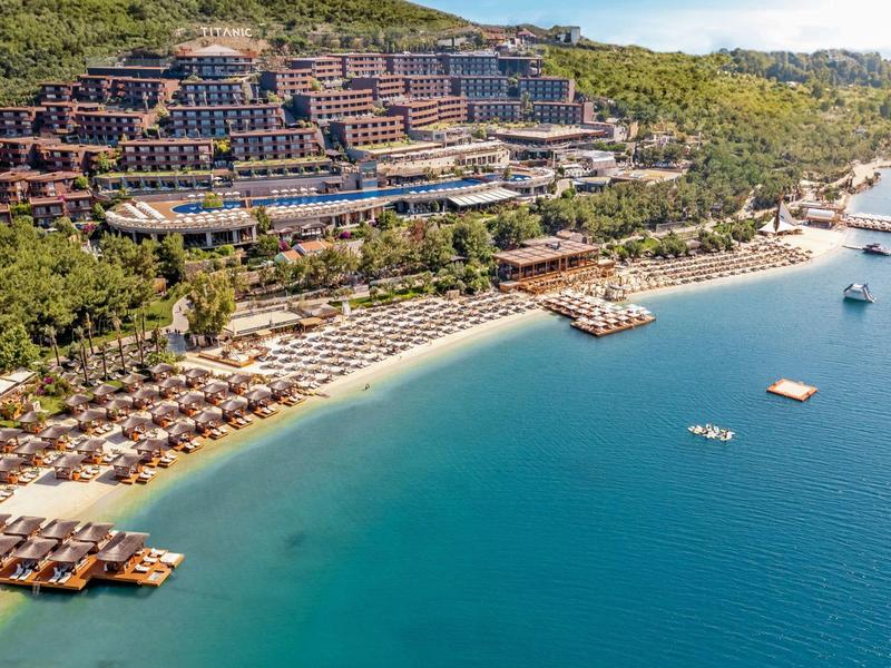 Luxury hillside resort with beach, umbrellas, and clear blue water