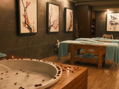 Luxuriöser Spa-Raum mit Whirlpool und Massagebetten, dekoriert mit Wandkunst und sanfter Beleuchtung.