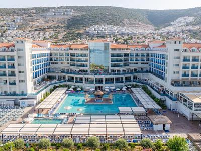 Modernes Hotel mit großem Poolbereich und umliegenden Bergen im Hintergrund.