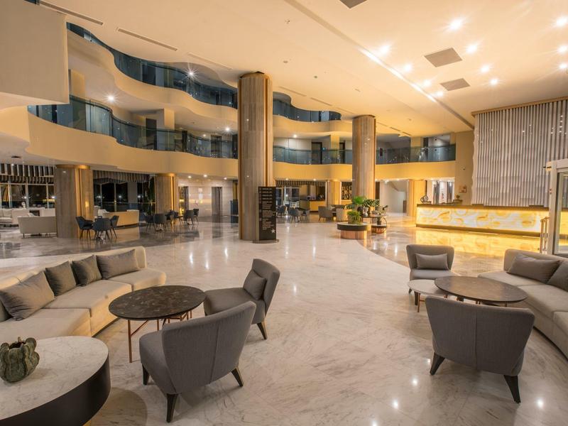Prostorná hotelová hala s moderním posezením a mramorovými sloupy.