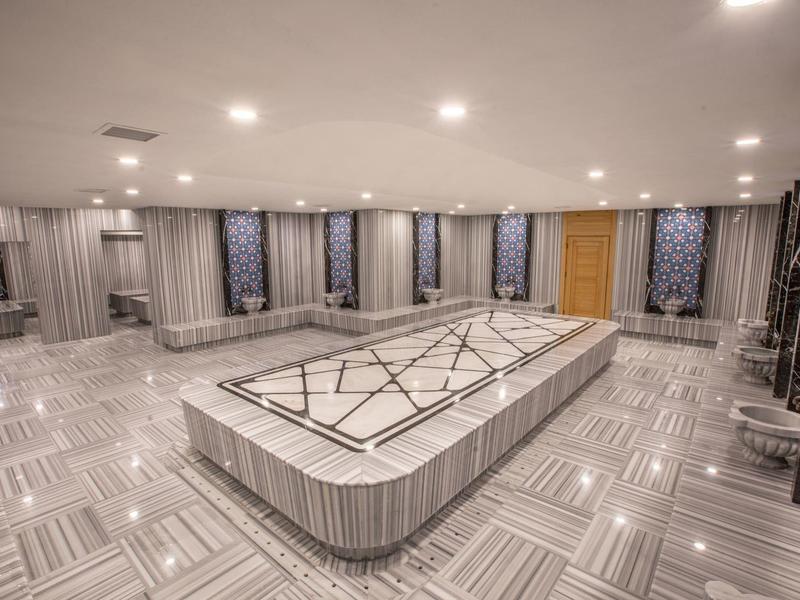 Prostorná světlá místnost s velkým centrálním stolem a křesly kolem, moderní atmosféra.