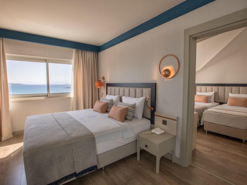 Hotelové pokoje s manželskými postelemi, výhledem na moře a moderním interiérem.