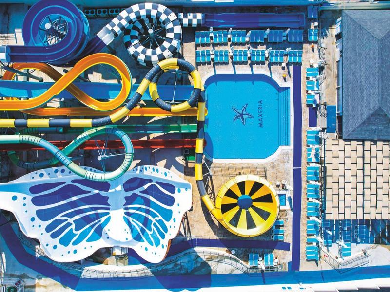 Letecký pohled na barevný aquapark s bazény a skluzavkami.