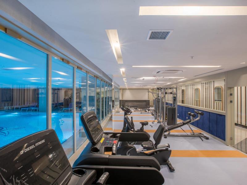 Interiér moderní posilovny s běžeckými pásy a výhledem na bazén.