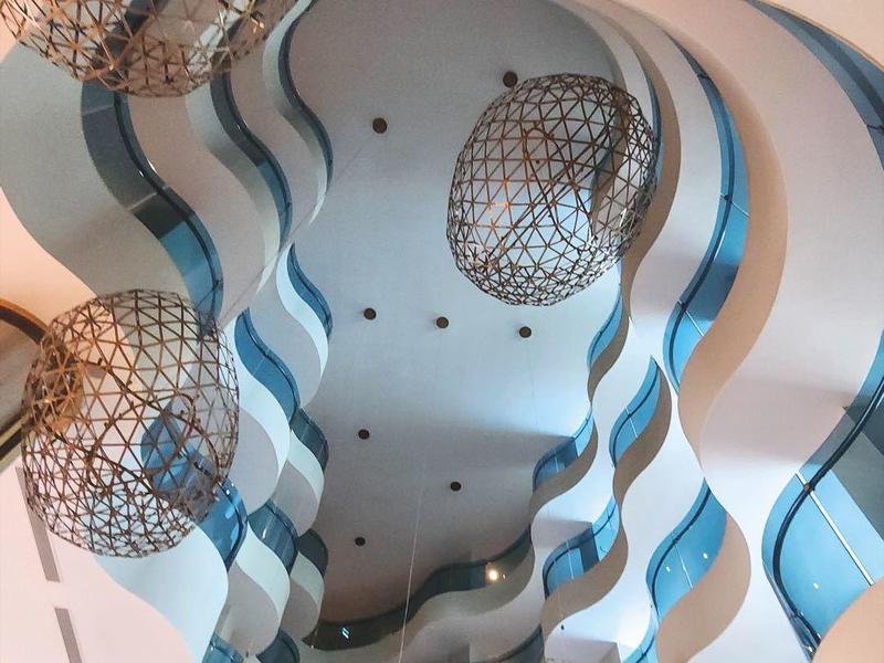 Vlnitý strop s originálními závěsnými svítidly v moderním interiéru.