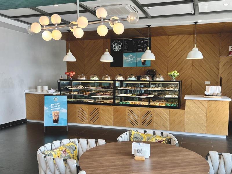 Moderní interiér kavárny s dřevěným pultem a kulatými židlemi.