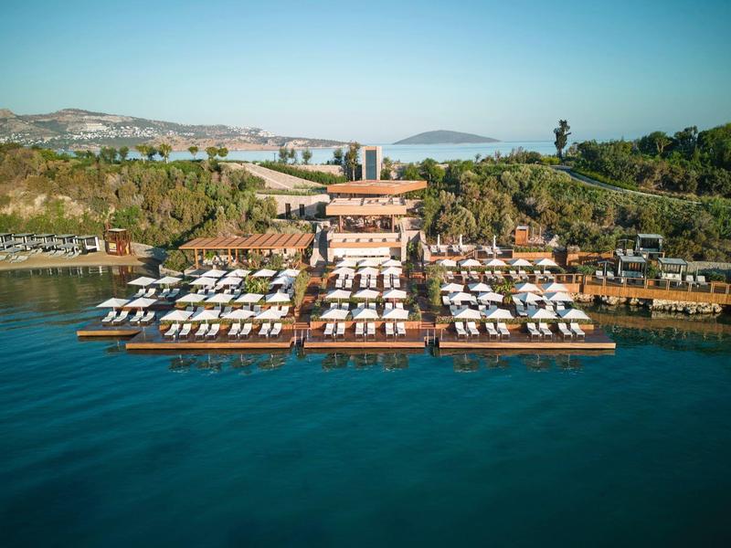 Resort de lujo con tumbonas en muelles junto al agua y vegetación exuberante detrás.