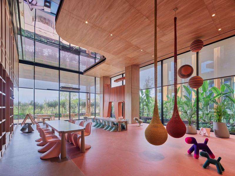 Moderna recepción de hotel con grandes ventanales, muebles de diseño y decoraciones colgantes.