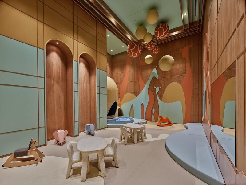 Sala de bienestar moderna con taburetes de madera redondos, chaise longue azul y decoración colorida en la pared.