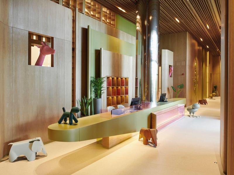 Pasillo con diseño moderno de madera, taburetes coloridos y plantas decorativas.