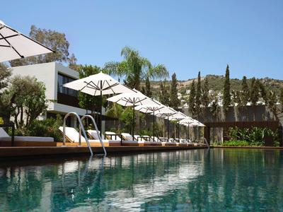 Piscina moderna de hotel con tumbonas y sombrillas en un día soleado.