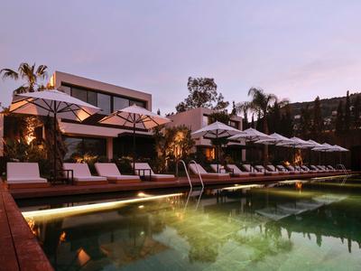 Área moderna de piscina con tumbonas y sombrillas al atardecer en un hotel.